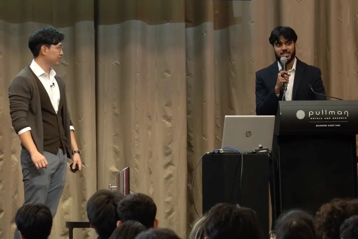 Tanzeer presenting at a podium, with another presenter on stage